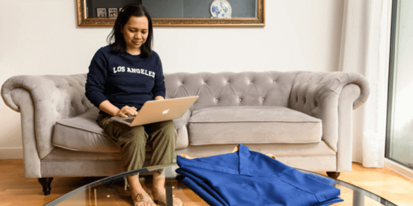 Woman sitting on a grey sofa while using her laptop