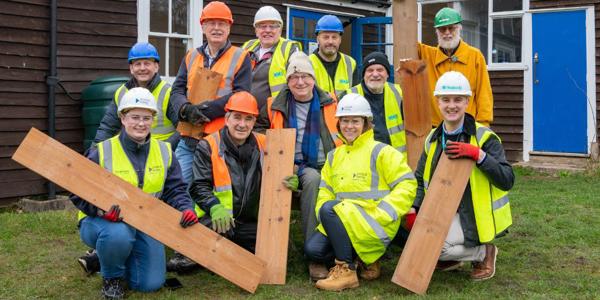 Group of people wearing hard hats and holding wood