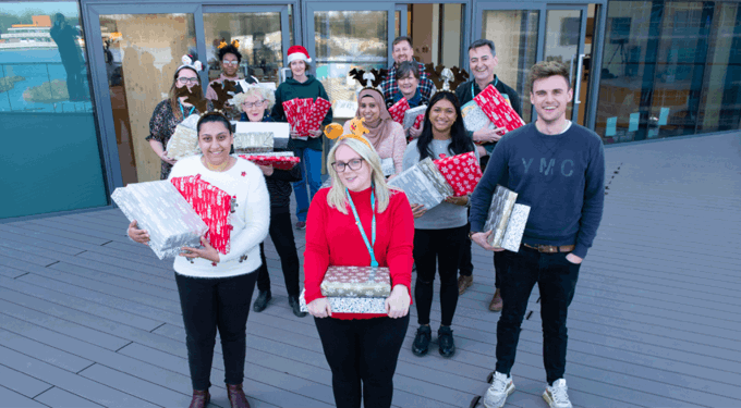 Group of people standing and smiling at the camera, holding presents