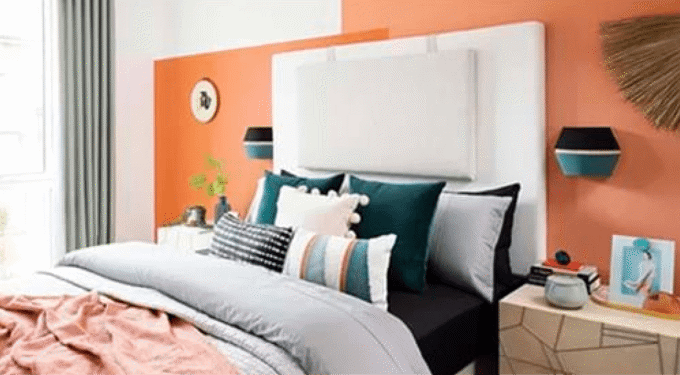 Room with an orange wall and a bed