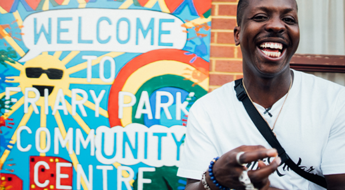 Man smiling in front of a sign saying Welcome to Friary Park community centre