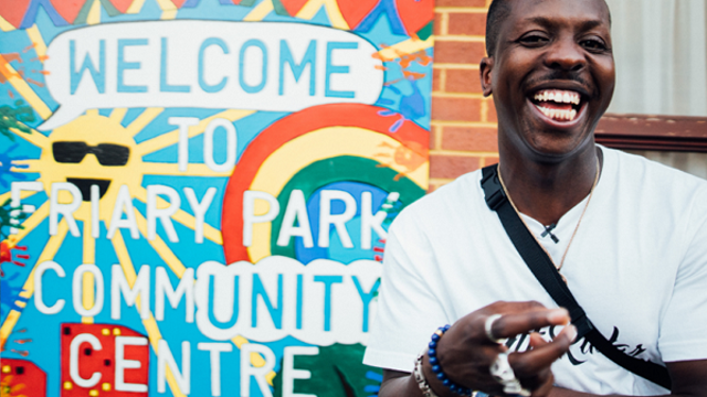 Man smiling in front of a sign saying Welcome to Friary Park community centre