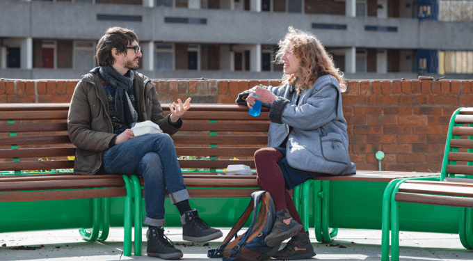 People sitting on a bench talking to each other