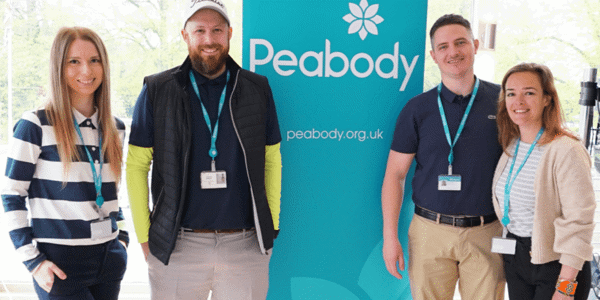 People smiling at the camera, while standing next to a Peabody sign