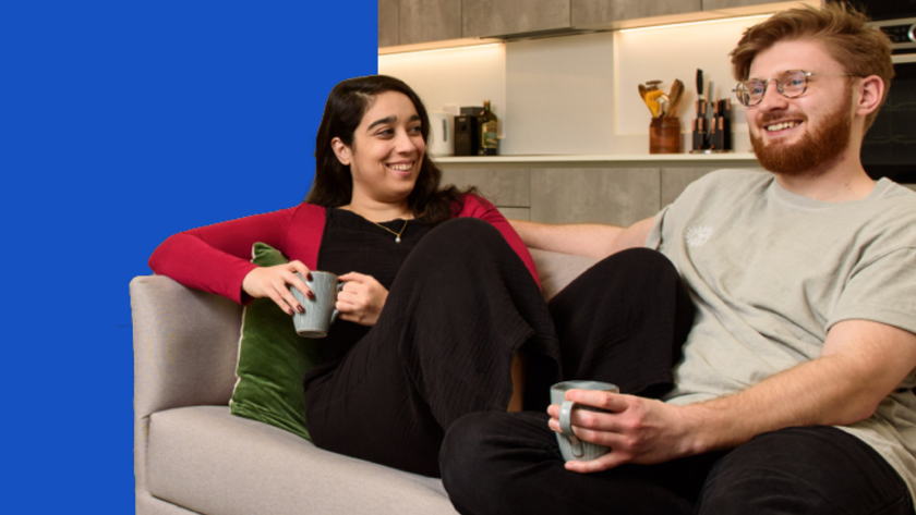 Man and woman sitting on a beige sofa, smiling