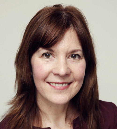 Headshot of a woman in a purple top, smiling