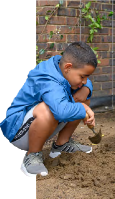 Boy in blue jacket digging in mud