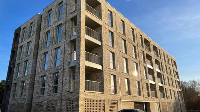 Tall beige building and a parked car